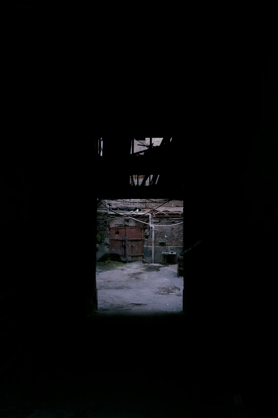 Dark alley with a single lit window in an old stone building at night