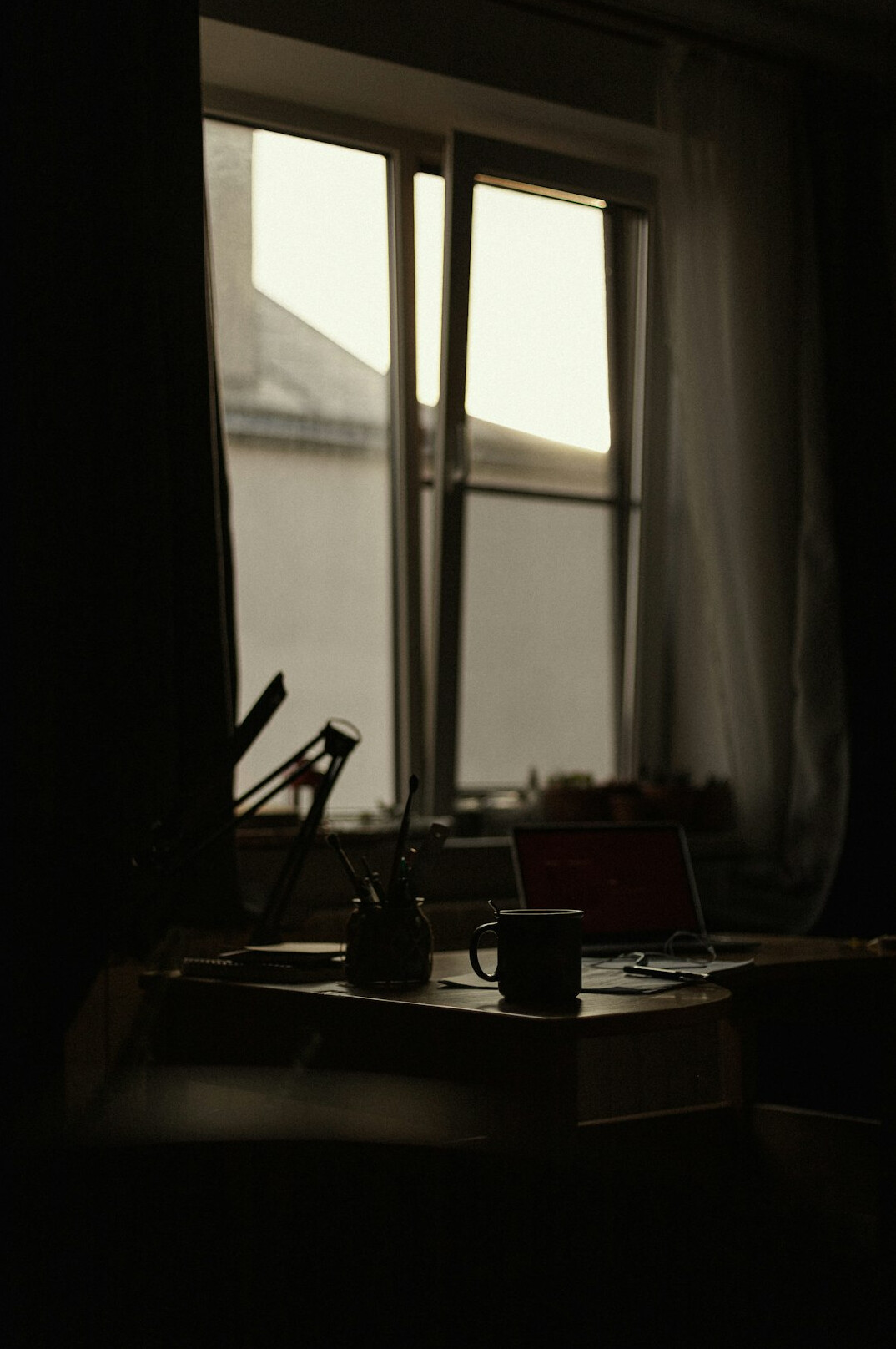 Writer's desk with typewriter, notebooks and coffee cup in dim evening light