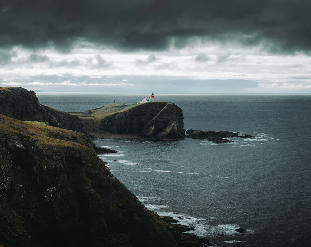 Abandoned lighthouse on a rocky cliff under a stormy sky
